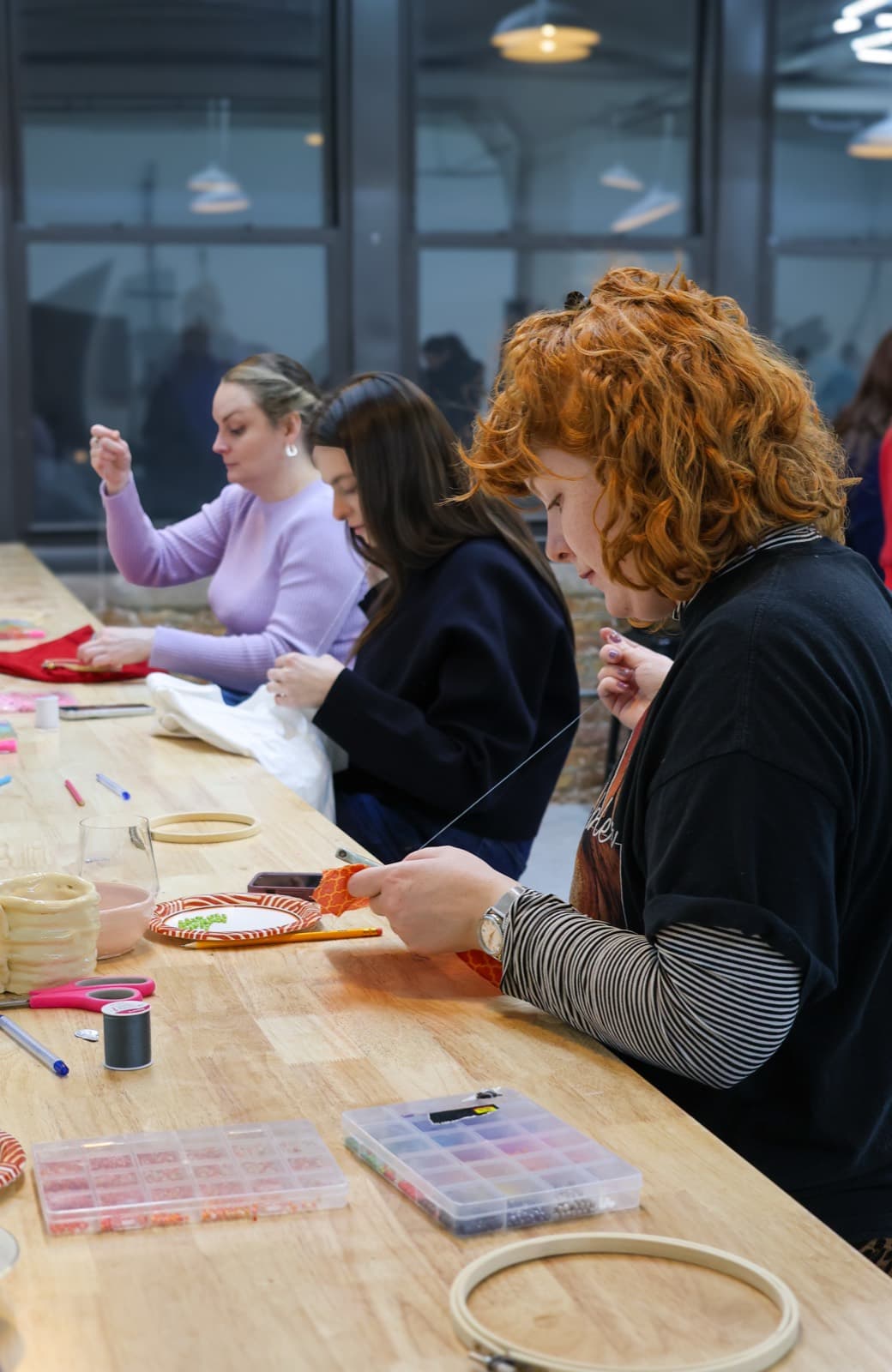 Student threading embroidery needle with focused concentration