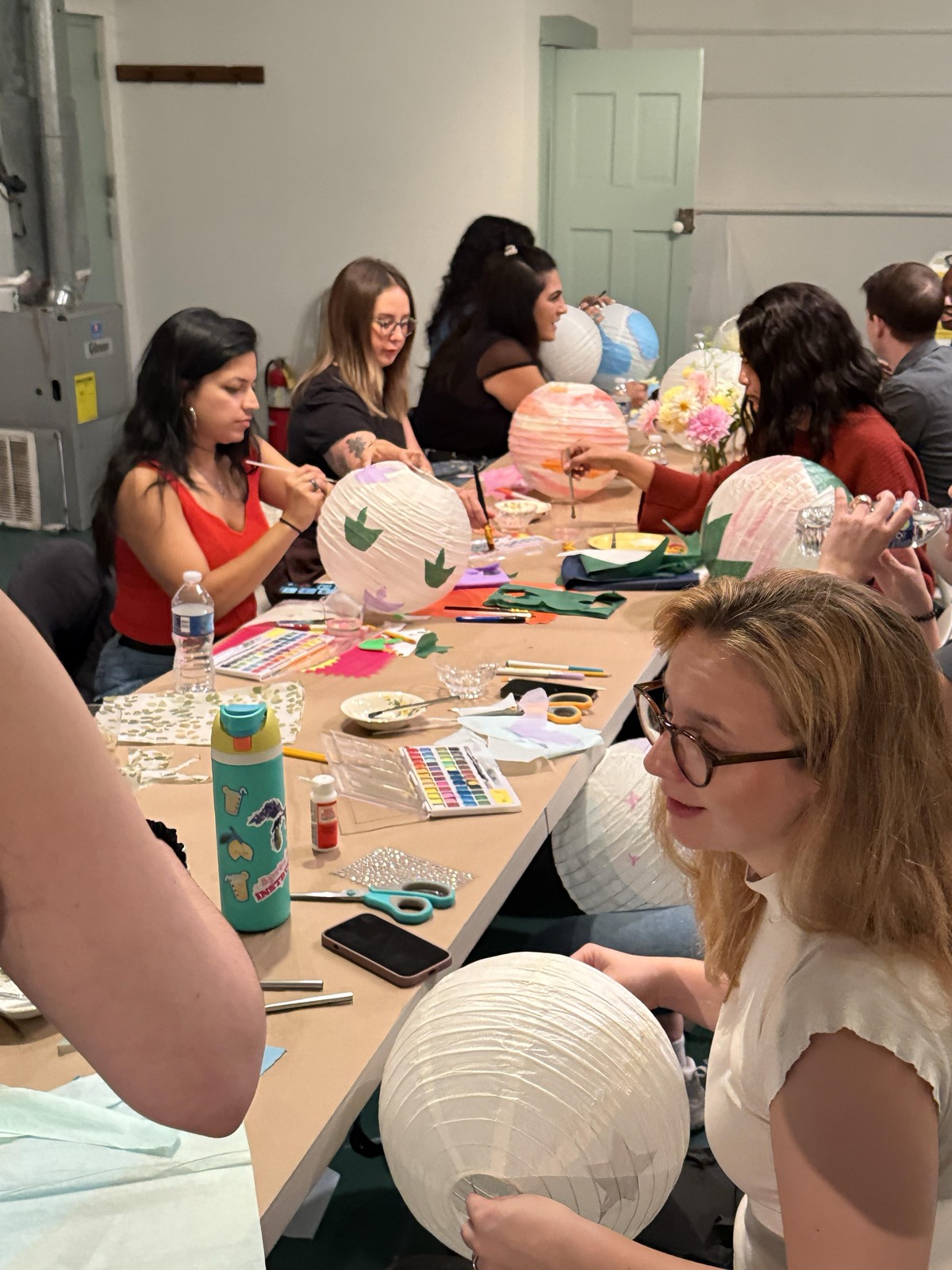 Guests painting paper lanterns around the studio table