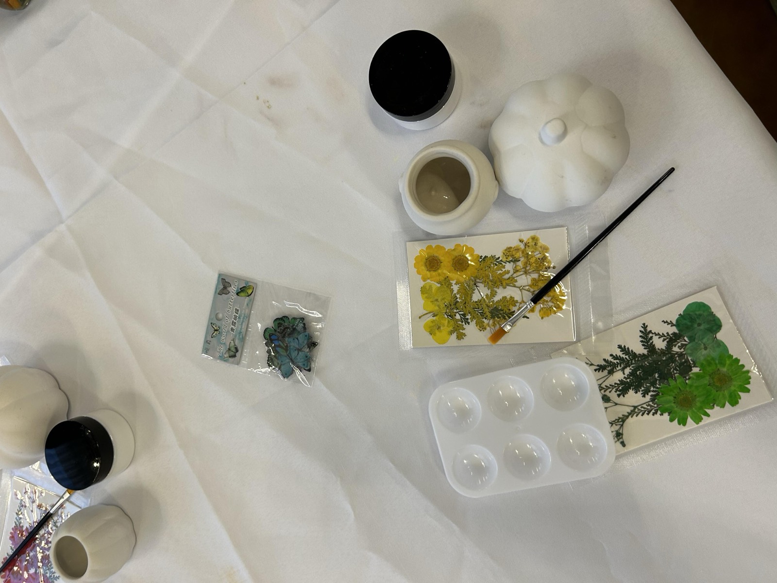 Mini ceramic pumpkins, pressed flowers, brushes and sealant on the table